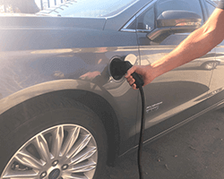hand plugging ev charger into vehicle